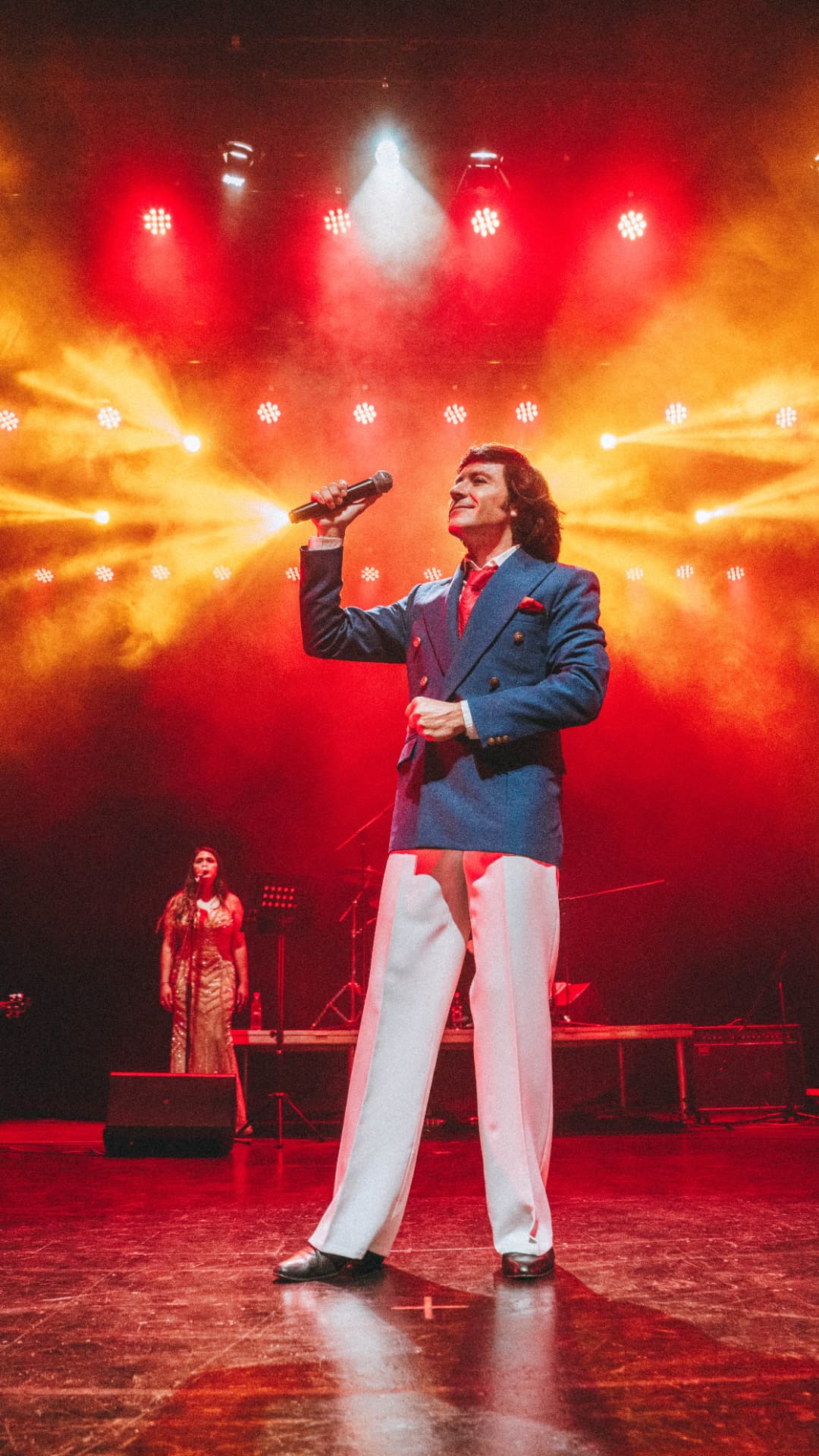 Presentación en escenario con blazer azul bajo luces rojas